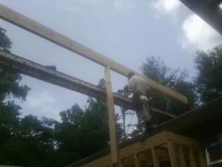 Carpenter setting a ridge beam over a new addition frame — Ice Dam Removal by Roofing Brothers in Munford