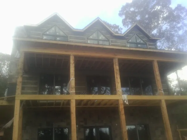 Dormers and porch framing on a large log home under construction — Roof Coating work by our crew in Munford