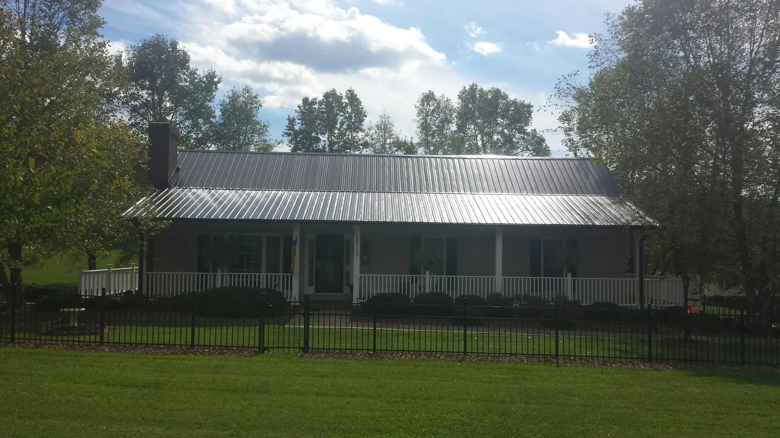Gray metal roof on a brick ranch with a full width front porch — Gutter Guard Installation work by our crew in Munford