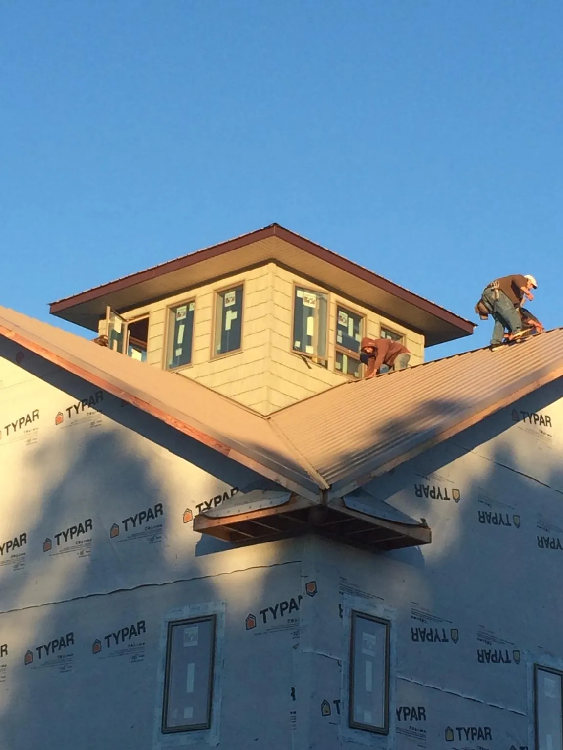 Roofers working around a rooftop cupola on a new metal roof at sunset — Roof Waterproofing in Munford by Roofing Brothers